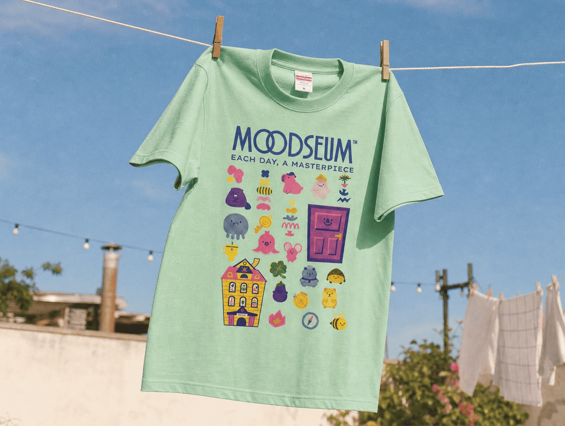 푸른 하늘 아래 걸린 민트색 Moodseum 티셔츠